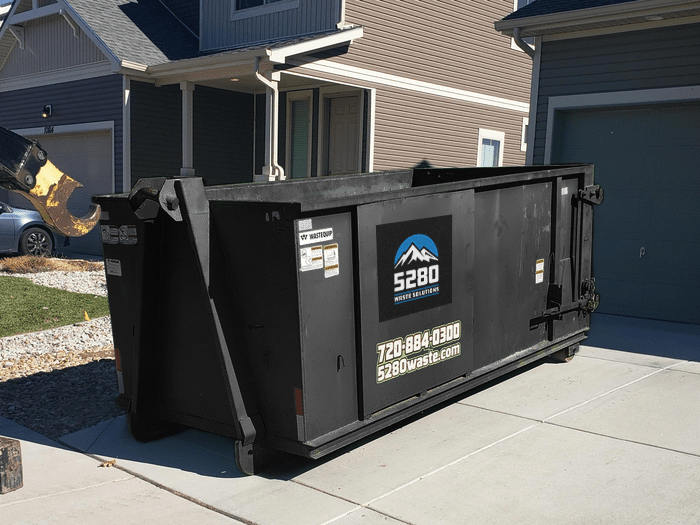 10 yard roll-off container ready for yard waste removal in Denver, CO, Crew loading a Roll-Off Dumpster at an Erie - CO home during a renovation cleanup
